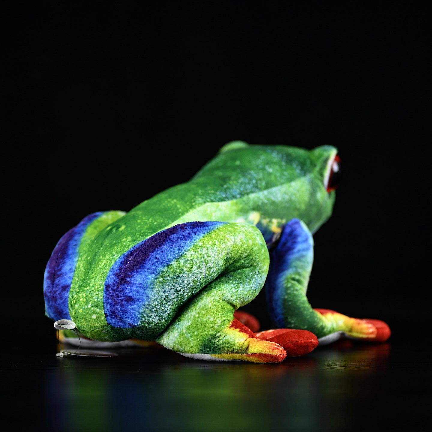 Back view of a lifelike red-eyed tree frog plush showcasing detailed green, blue, and orange patterns