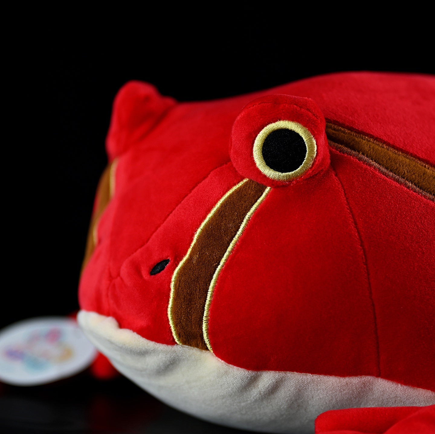 Detail shot of tomato frog plush’s eye and stripe pattern, emphasizing intricate and realistic craftsmanship