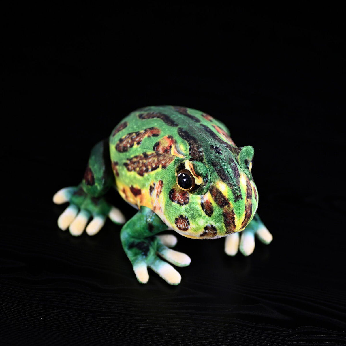 Vista dall'alto di un peluche di rana cornuta riccamente decorato, che cattura le sue caratteristiche uniche per un'esperienza di gioco realistica con un giocattolo a tema animale.