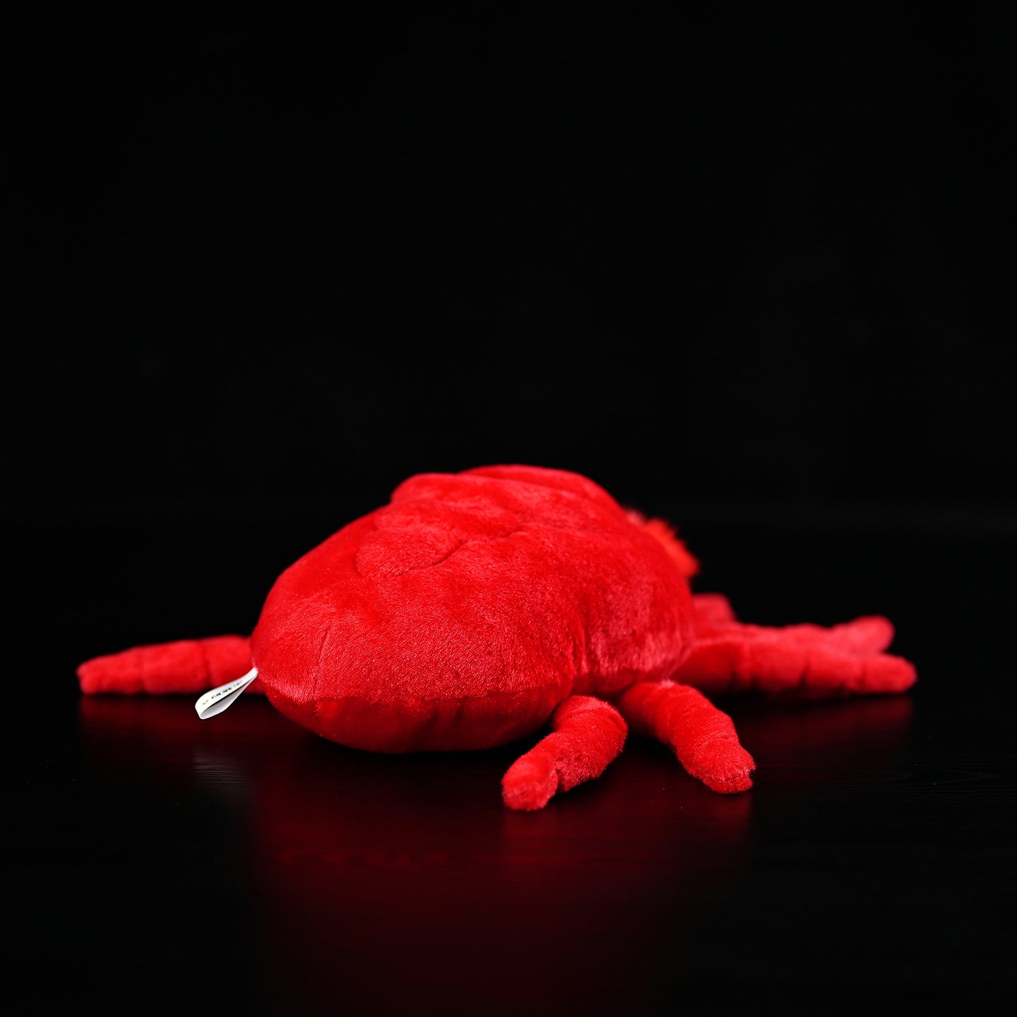 Rear view of red velvet mite plush toy, emphasizing its lifelike design and vibrant red finish