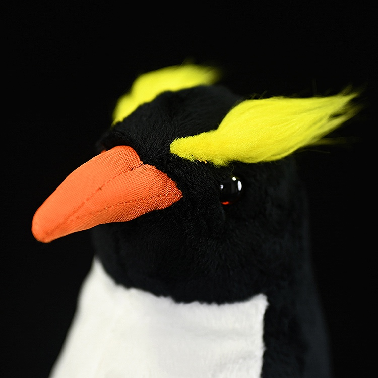 Close-up of a Fiordland penguin plush head by SoftDaysLab, featuring striking yellow crests and orange beak