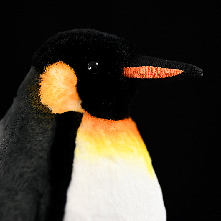 Detailed view of king penguin plush head, featuring bright orange cheek patches and a realistic orange beak