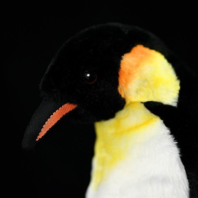 Close-up of emperor penguin plush face, showing intricate stitching and lifelike yellow ear patch details