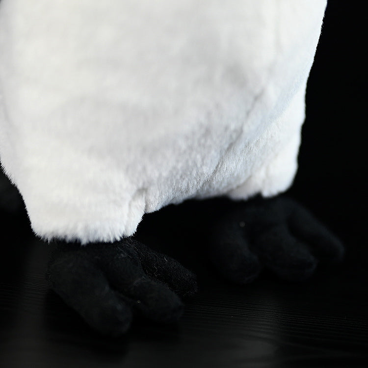 Bottom view of emperor penguin plush toy's soft feet and white belly, highlighting realistic craftsmanship