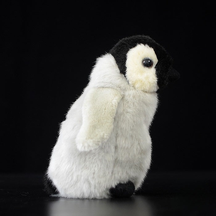 Side view of a realistic emperor penguin chick plush toy with soft, fluffy texture for animal lovers