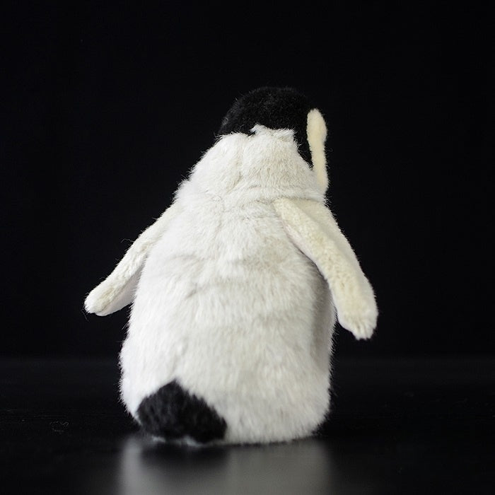 Back view of a cuddly emperor penguin chick plush, showcasing its soft and lifelike design