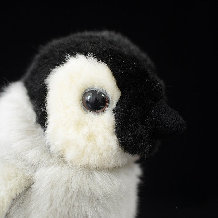 Close-up of a baby emperor penguin chick plush face, featuring realistic details and soft textures