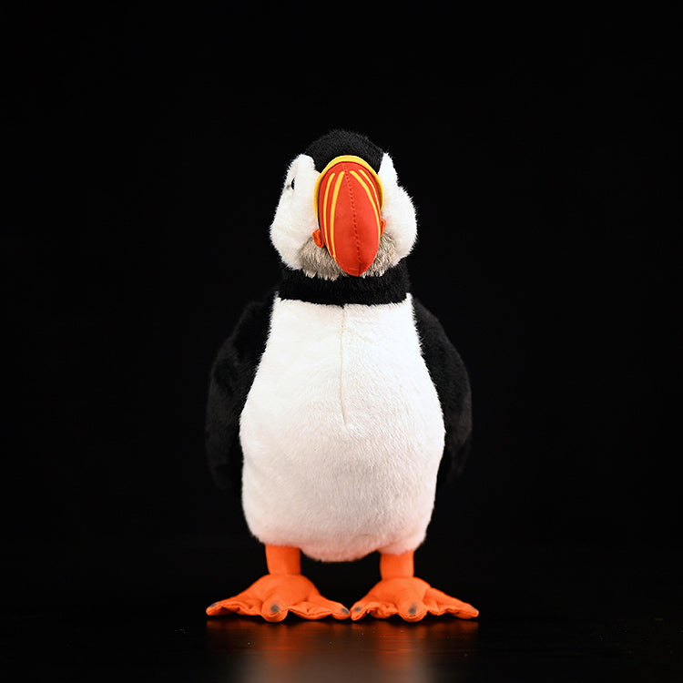 Front view of lifelike Atlantic puffin plush toy standing upright with bright orange feet