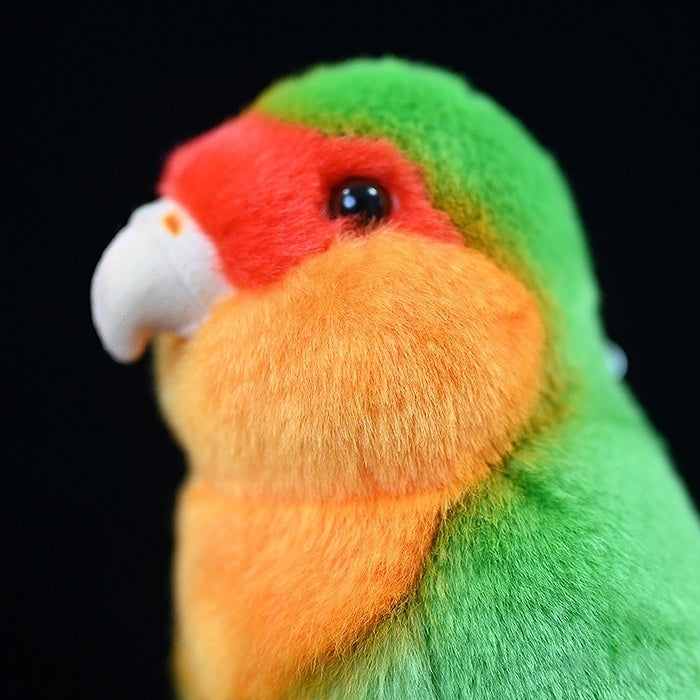 Left side close-up of a green lovebird plush toy’s head, showing intricate detailing and vibrant colors
