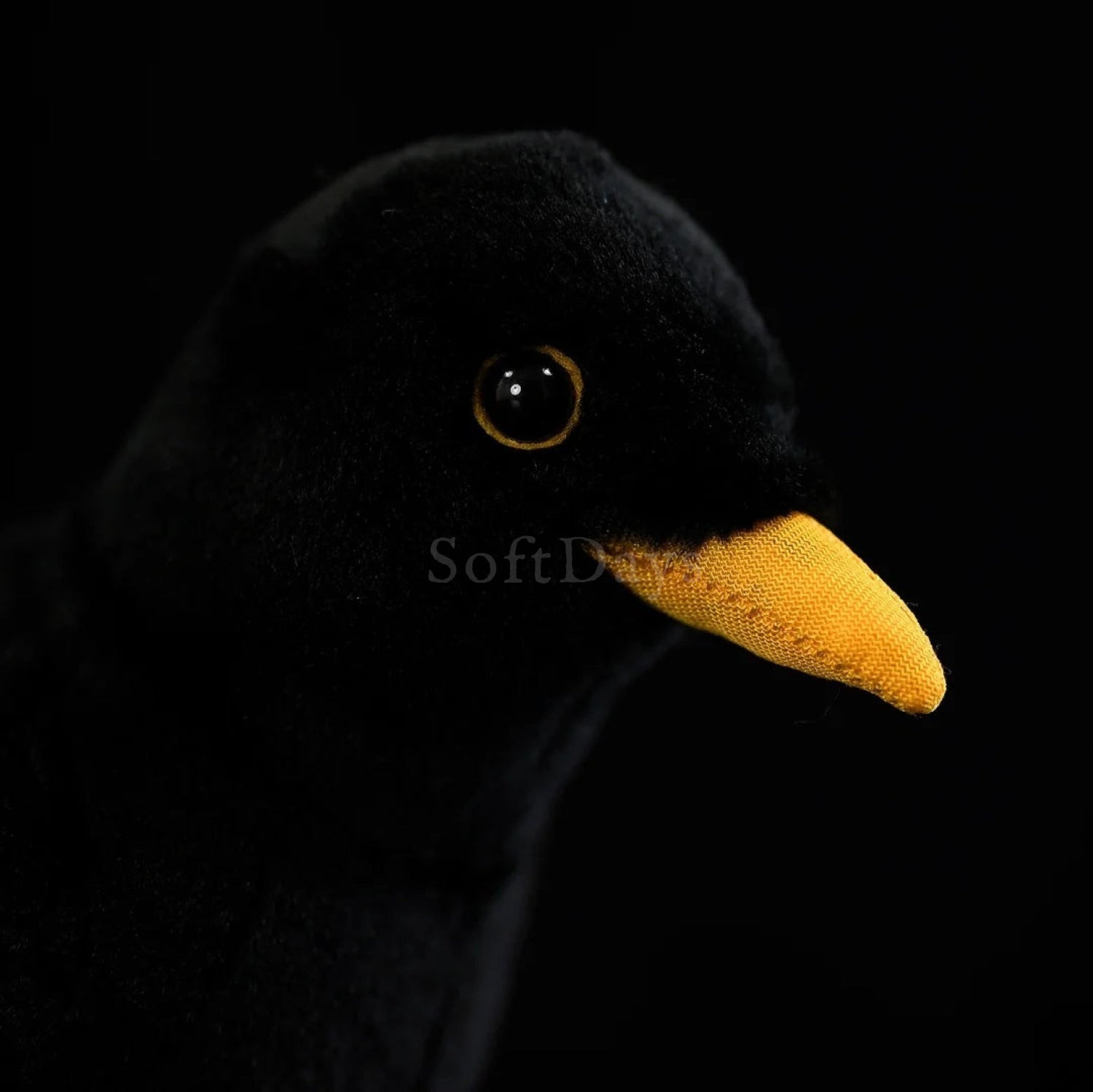 Close-up of the Eurasian Blackbird plush toy’s face with a bright yellow beak and soft black fur