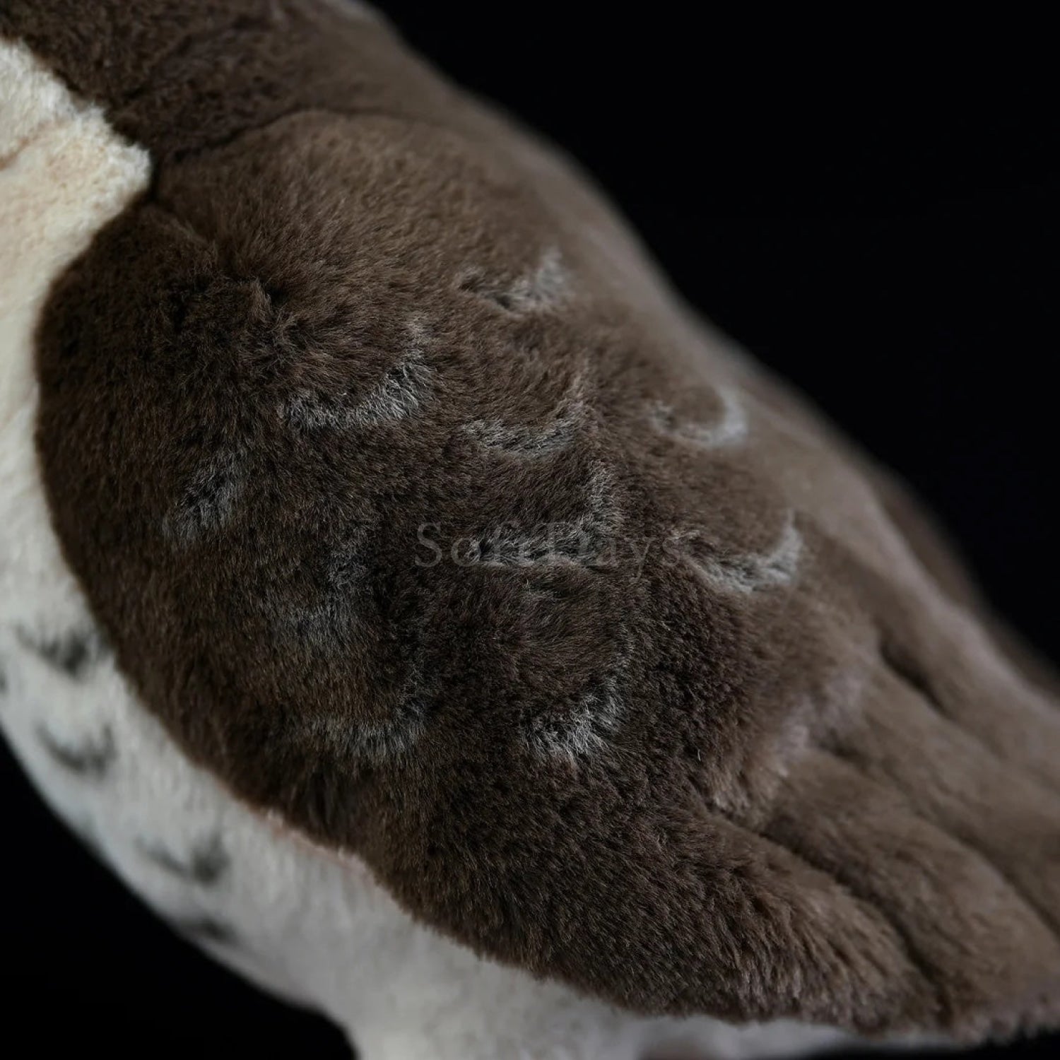 Close-up of lifelike peregrine falcon plush toy's soft gray wing feathers with intricate patterns