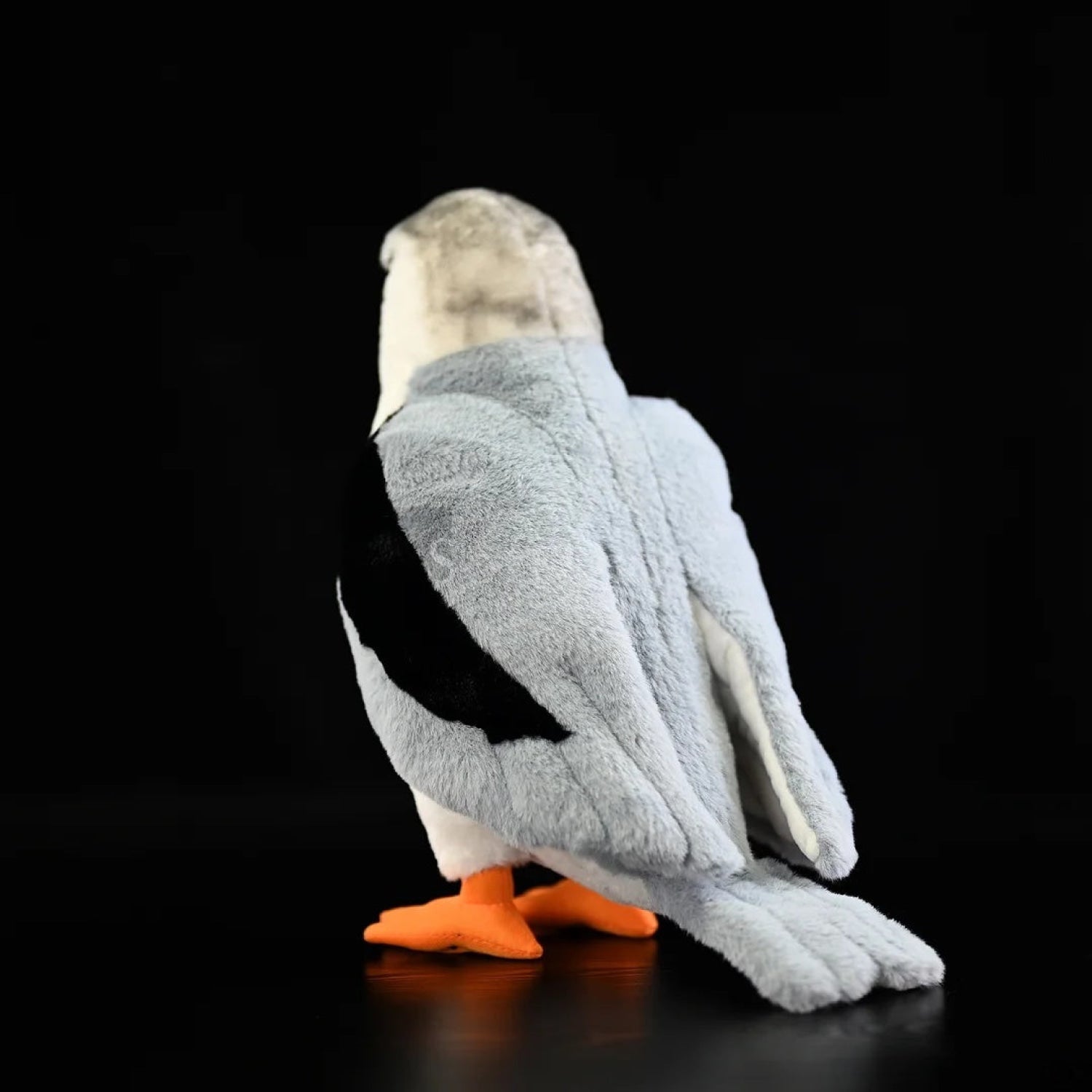 Back view of lifelike black-winged kite plush toy with grey wings, black patches, and a soft fluffy tail