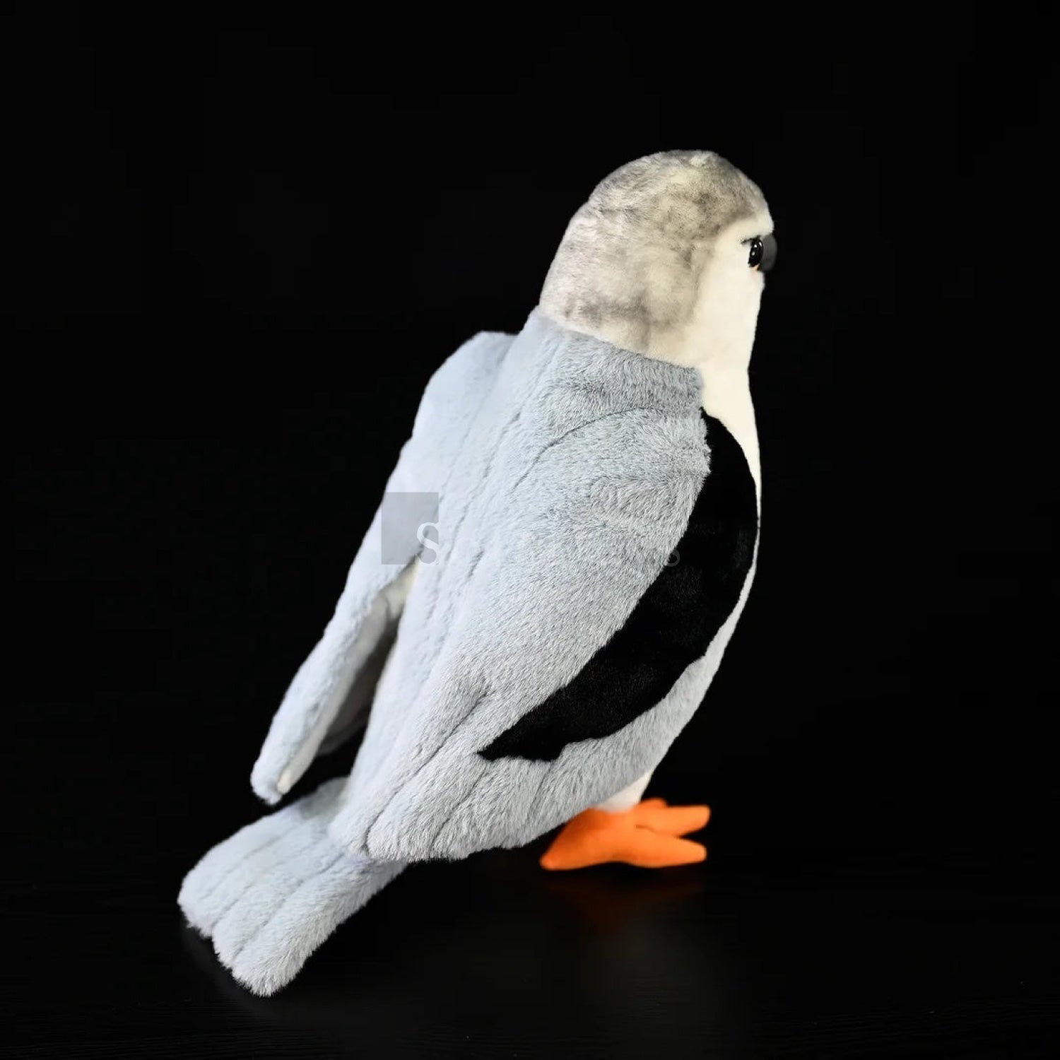 Rear view of lifelike black-winged kite plush toy featuring soft grey feathers, black wing details, and bright orange feet