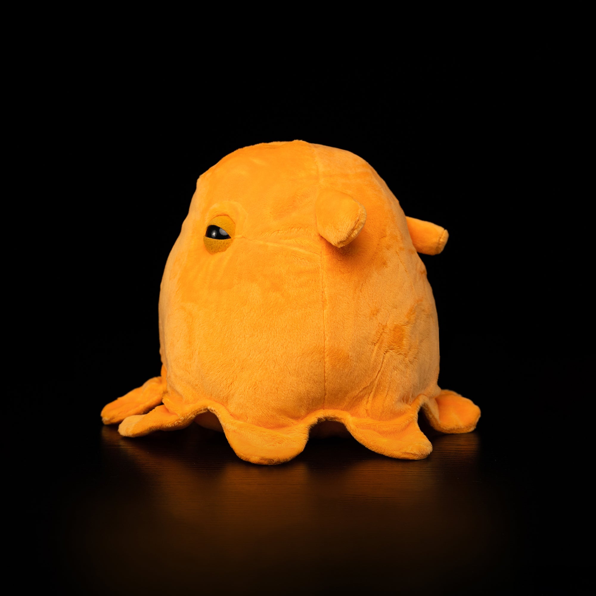 Side view of Dumbo Octopus plush toy by SoftDaysLab®, showcasing its adorable floppy fins and vibrant orange color