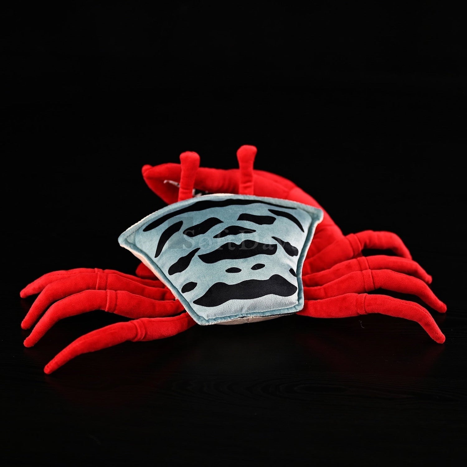 Top view of fiddler crab plush toy showing its striped shell and red legs, perfect for nature enthusiasts