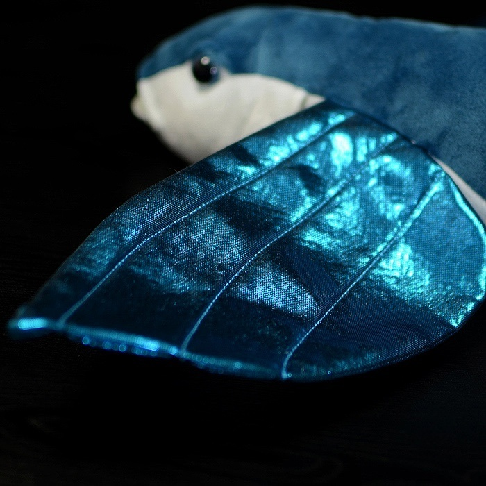 Close-up of the shimmering blue wings of a flying fish plush toy, capturing fine details