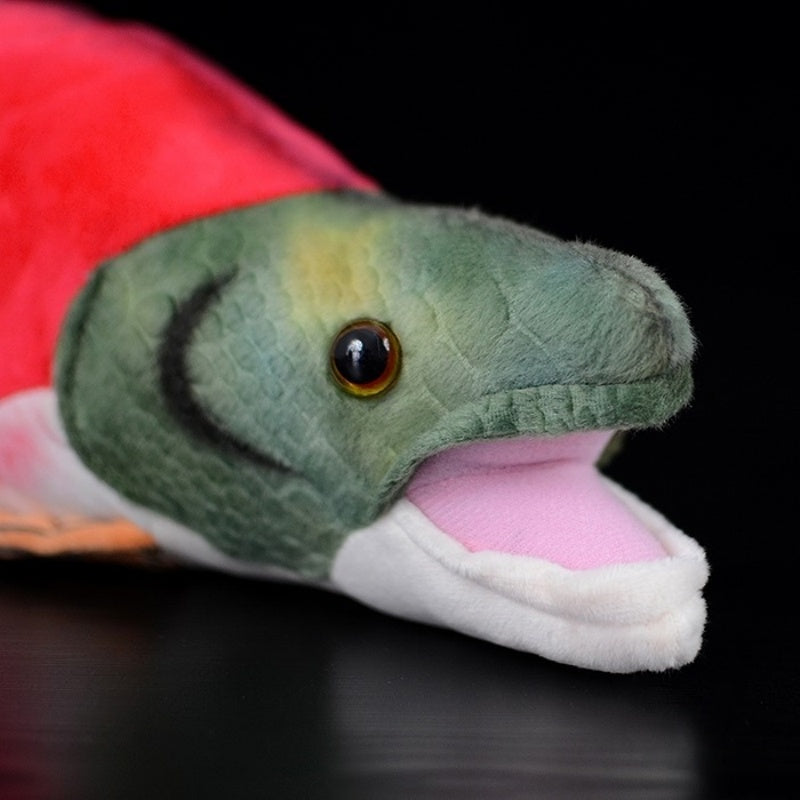 Close-up of the sockeye salmon plush toy’s face, with green head and realistic eye details