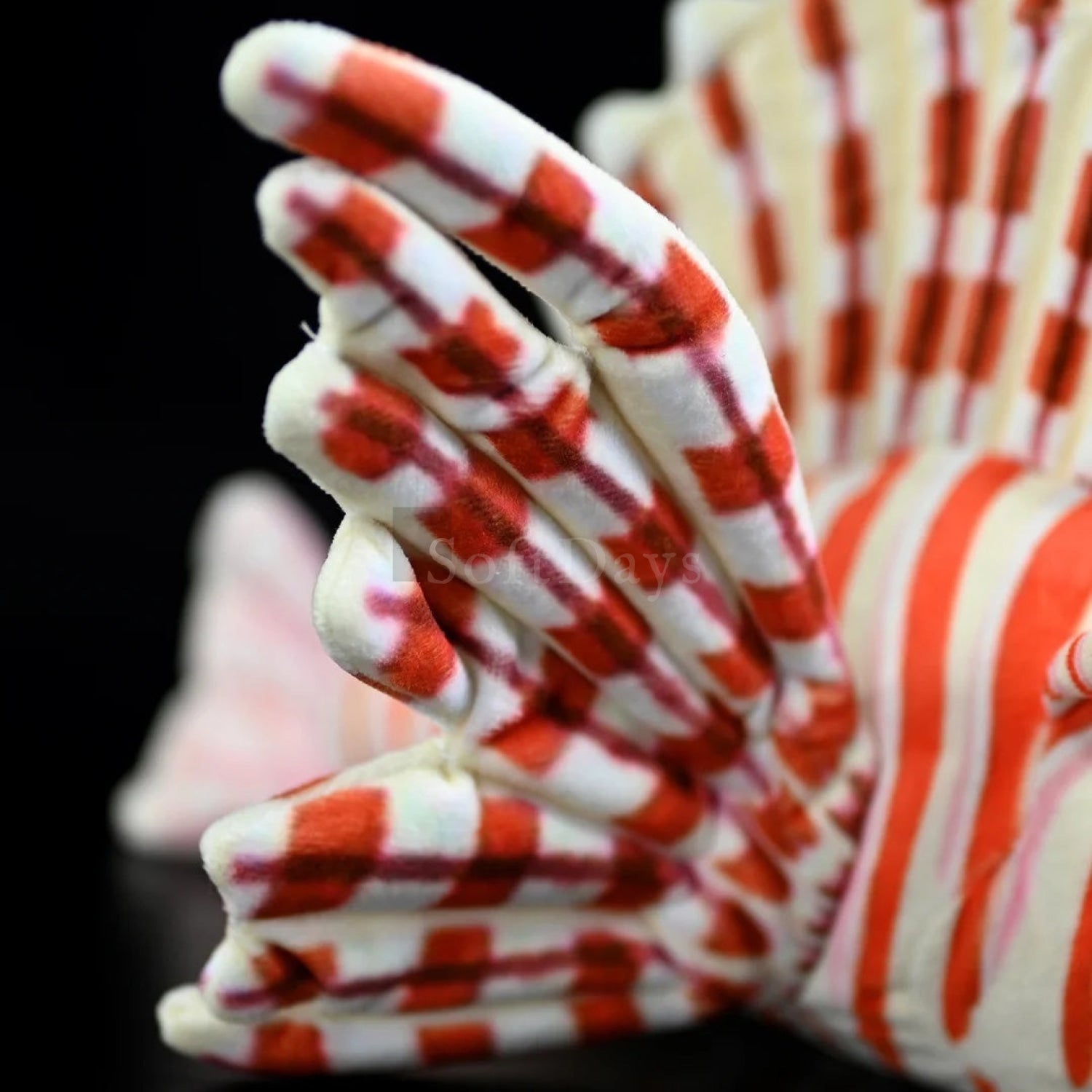Close-up of red lionfish plush toy’s tail, featuring bold stripes and soft, realistic design