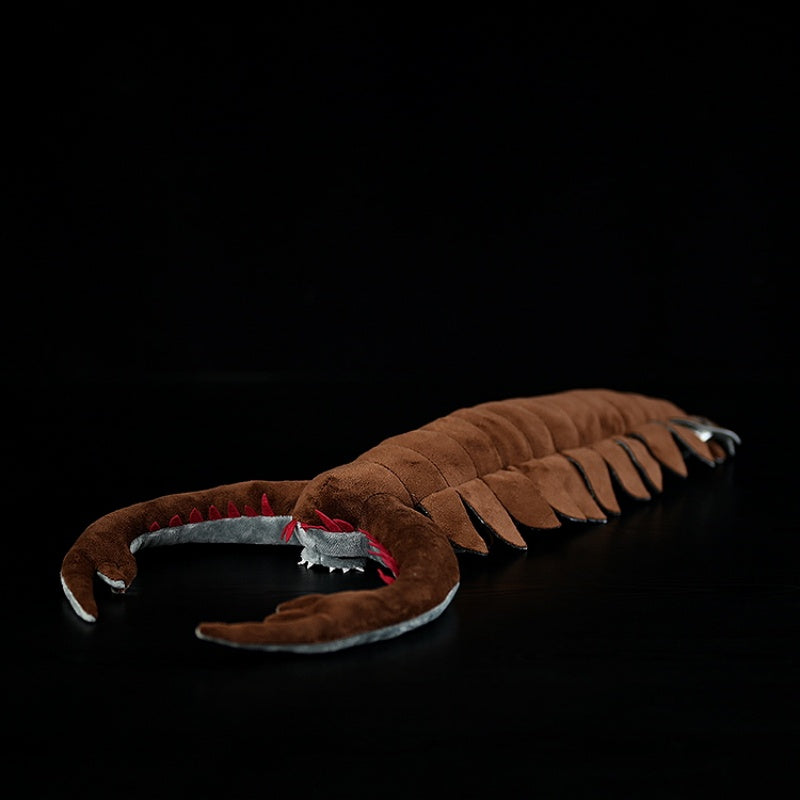 Side angle of the Omnidens plush toy highlighting its segmented body and talon-like mouth design