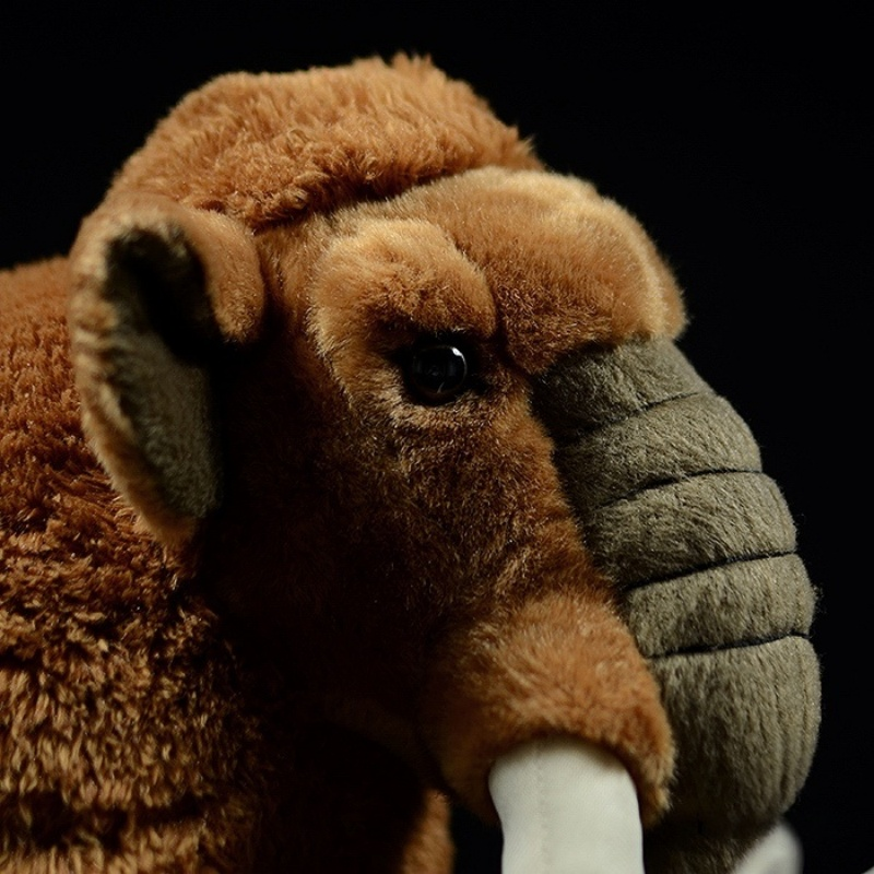 Close-up of woolly mammoth plush toy’s head with detailed eyes, tusks, and textured trunk