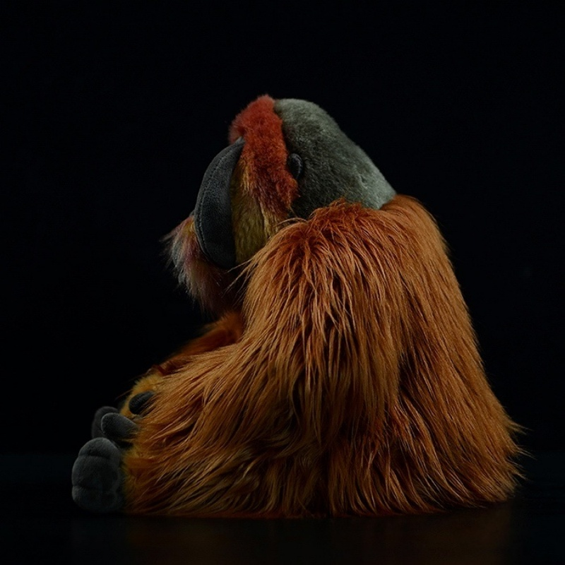 Side view of an orangutan plush toy sitting, showcasing its realistic fur texture and detailed features