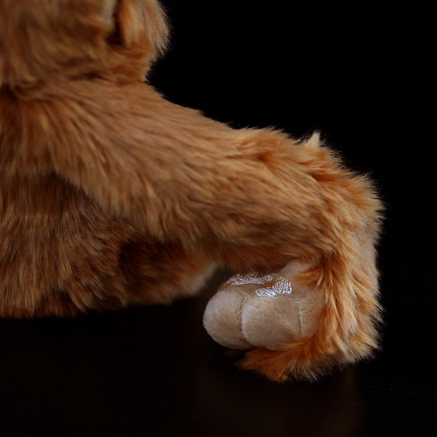 Close-up of orangutan plush hand, showcasing delicate stitching and soft fur for realistic jungle play