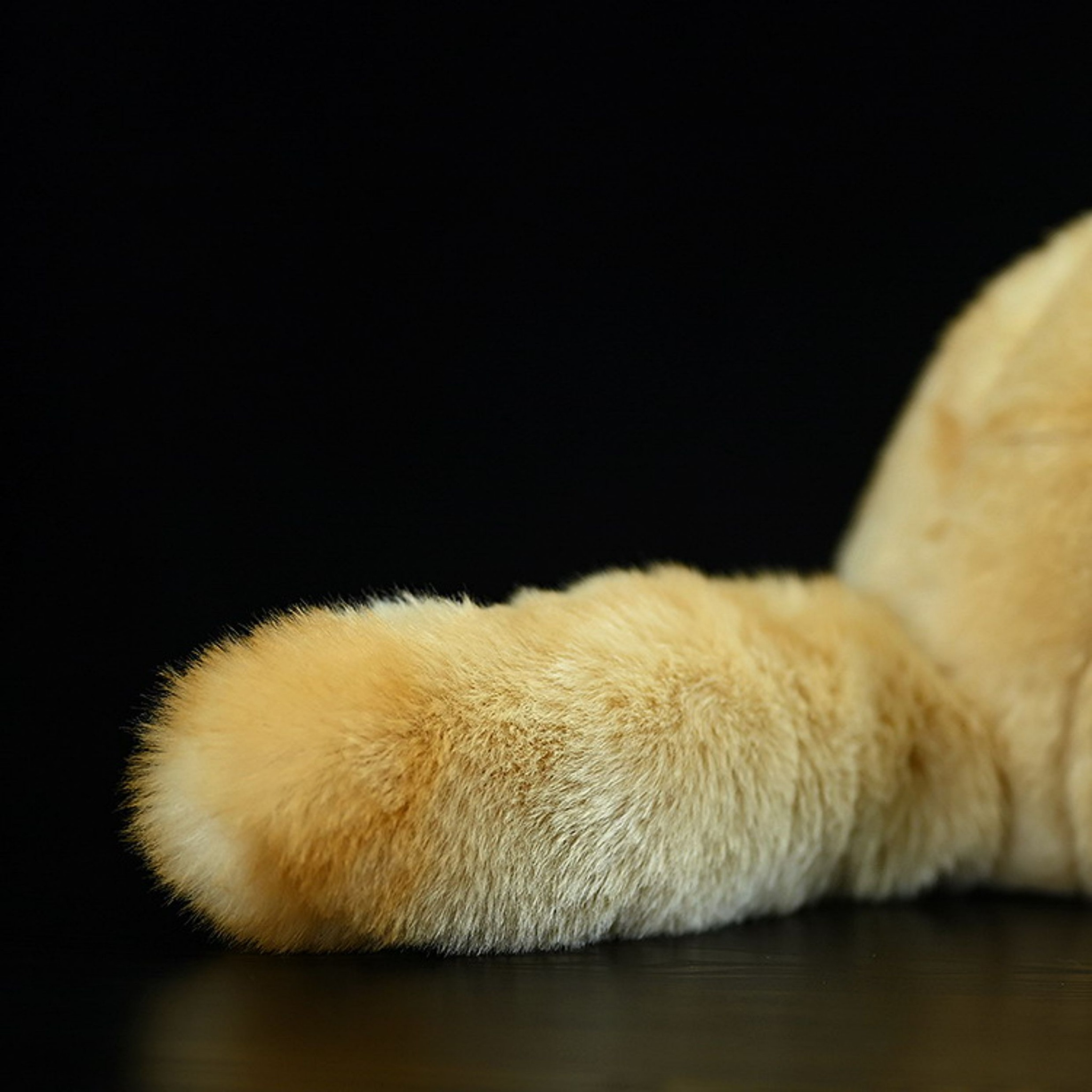 Close-up of the fluffy tail of a realistic fennec fox plush toy, perfect for cuddling