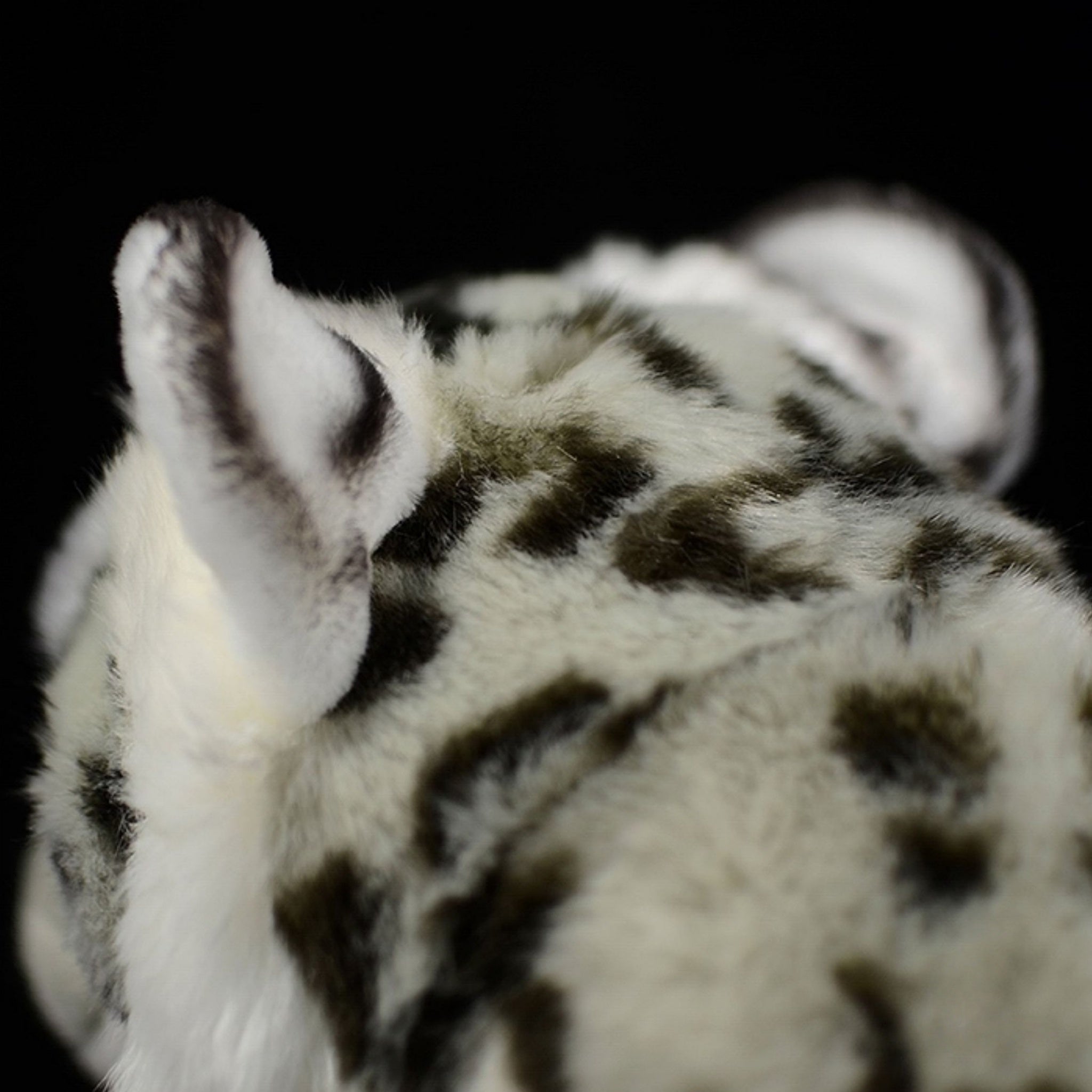Back view of snow leopard plush toy's head, showing detailed spots and soft, realistic fur texture