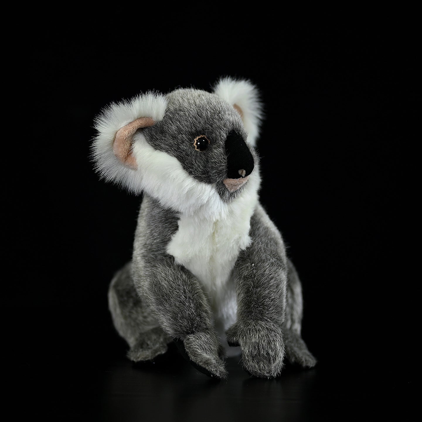 Side view of a lifelike koala plush toy with fluffy ears and a cute, realistic design