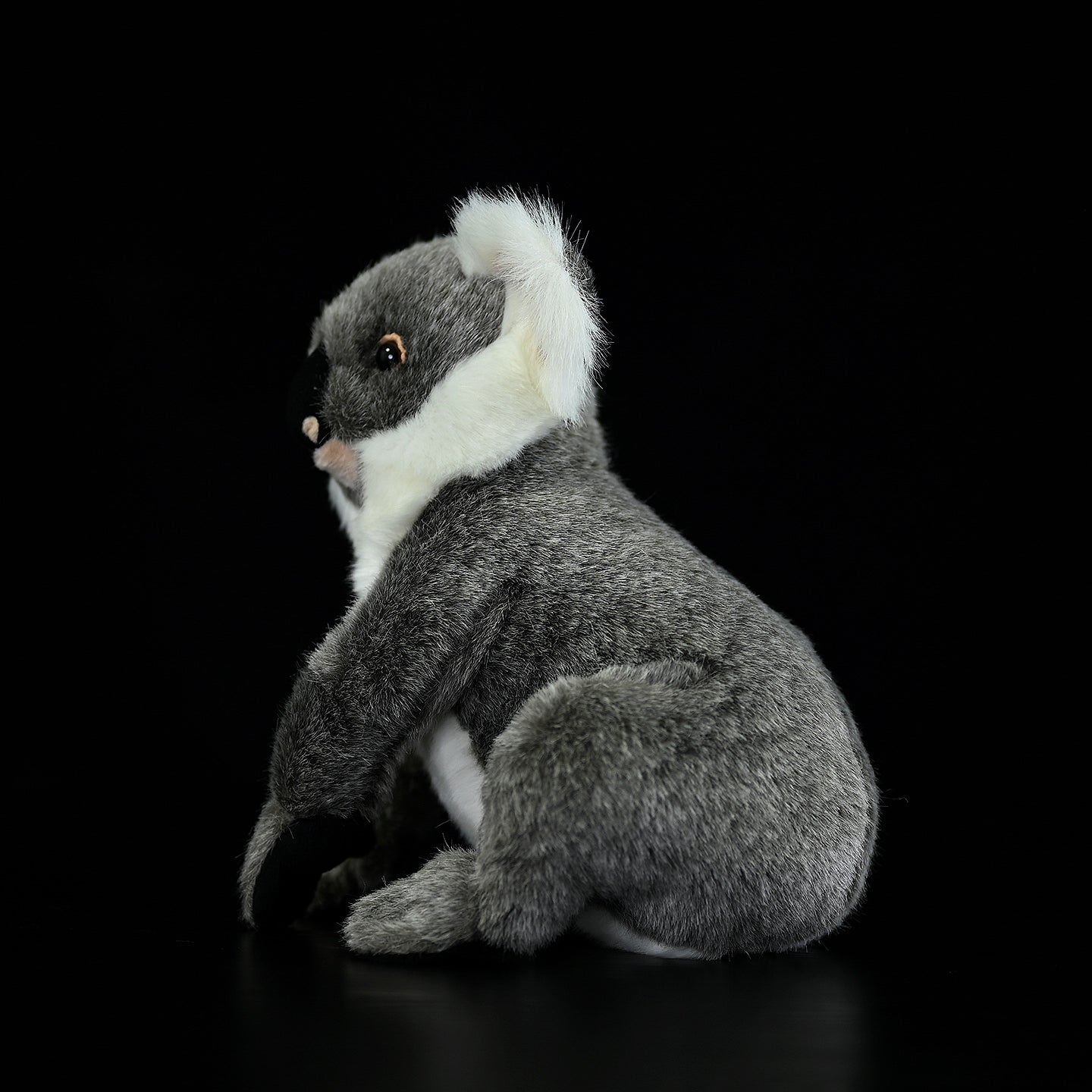 Lifelike koala plush toy sitting sideways, highlighting its realistic posture and fluffy texture