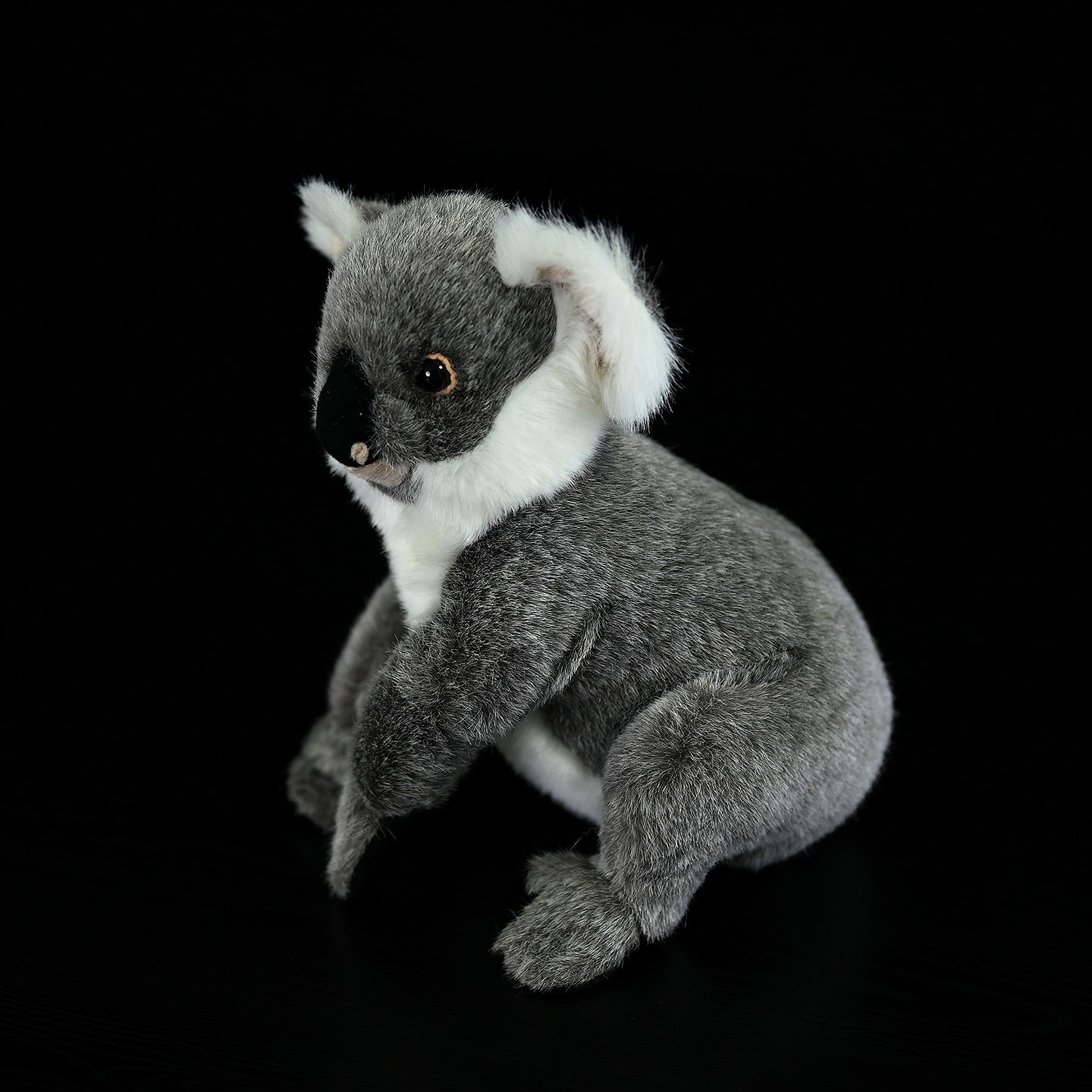 Side angle of a koala plush toy in a natural sitting pose, featuring lifelike fur and soft details