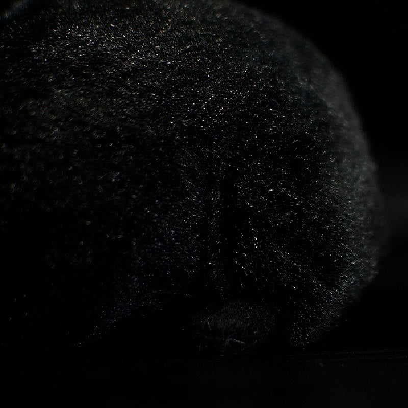 Back texture detail of the black rat plush toy, showing realistic fur and lifelike stitching