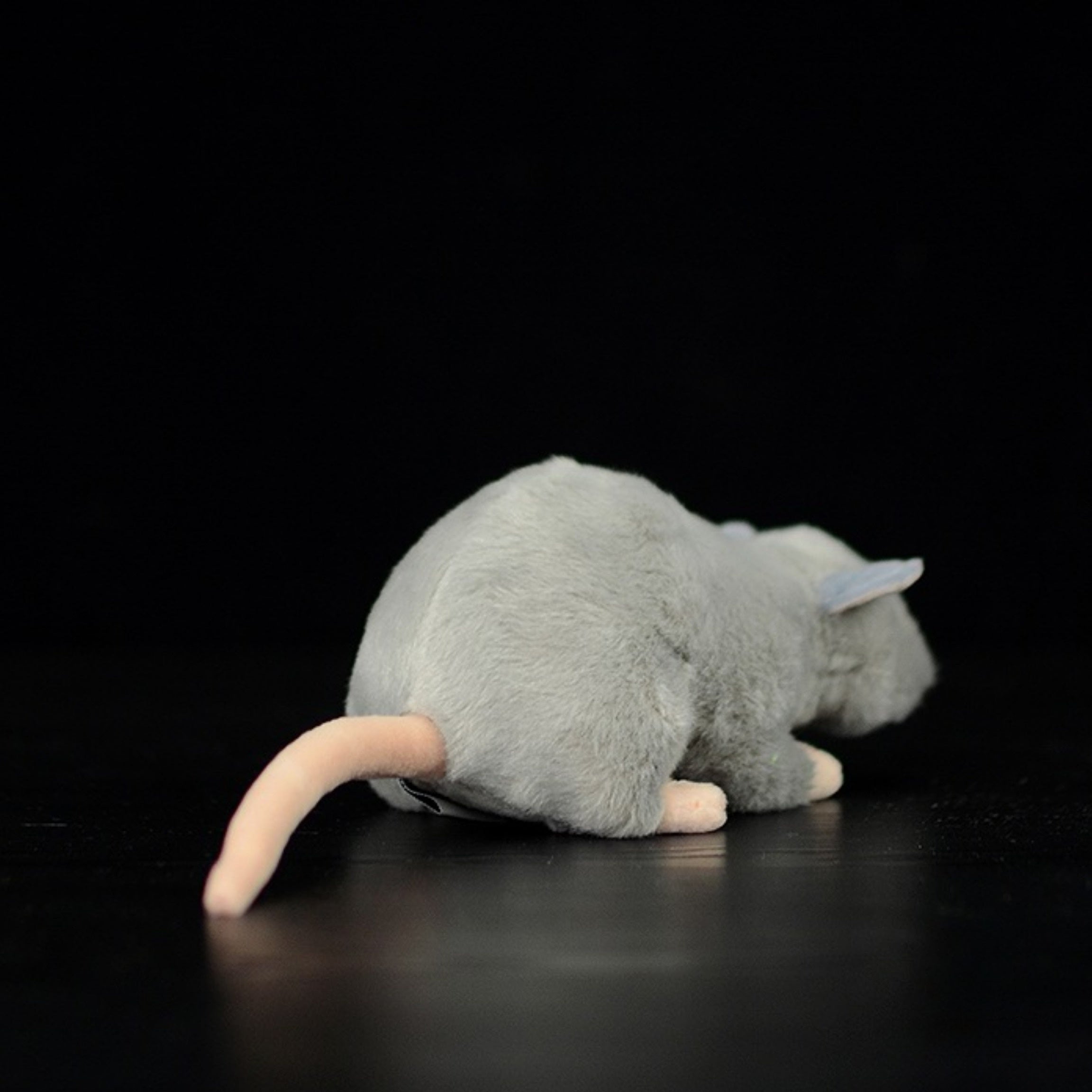 Rear view of the grey mouse plush toy, highlighting its soft fur and realistic tail placement