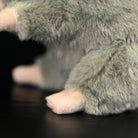Close-up of a standing grey mouse plush toy’s paws, showing its soft and delicate design