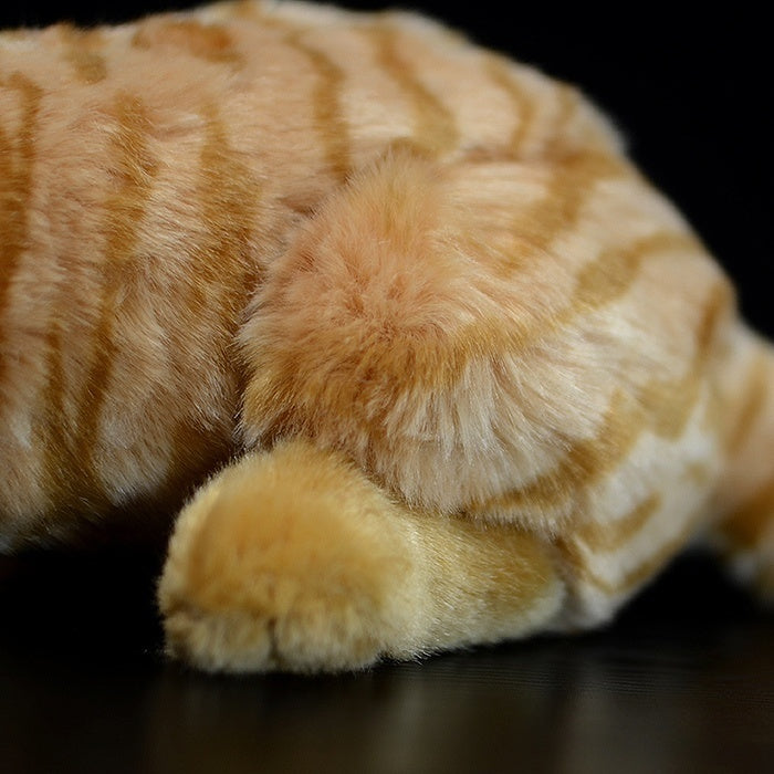 Close-up of the plush toy’s soft paw and striped body, resembling a real orange tabby cat