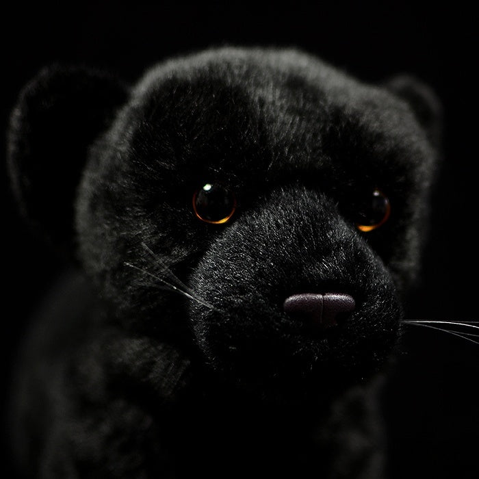 Close-up of a black panther plush face with lifelike eyes and soft fur, crafted for wildlife enthusiasts