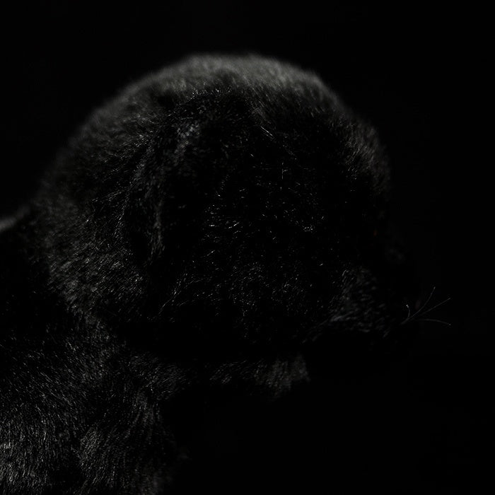 Side profile of a black panther plush toy, highlighting its smooth fur and realistic design for collectors