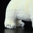 Close-up of the polar bear plush toy's paws, featuring realistic details and soft, cuddly fabric