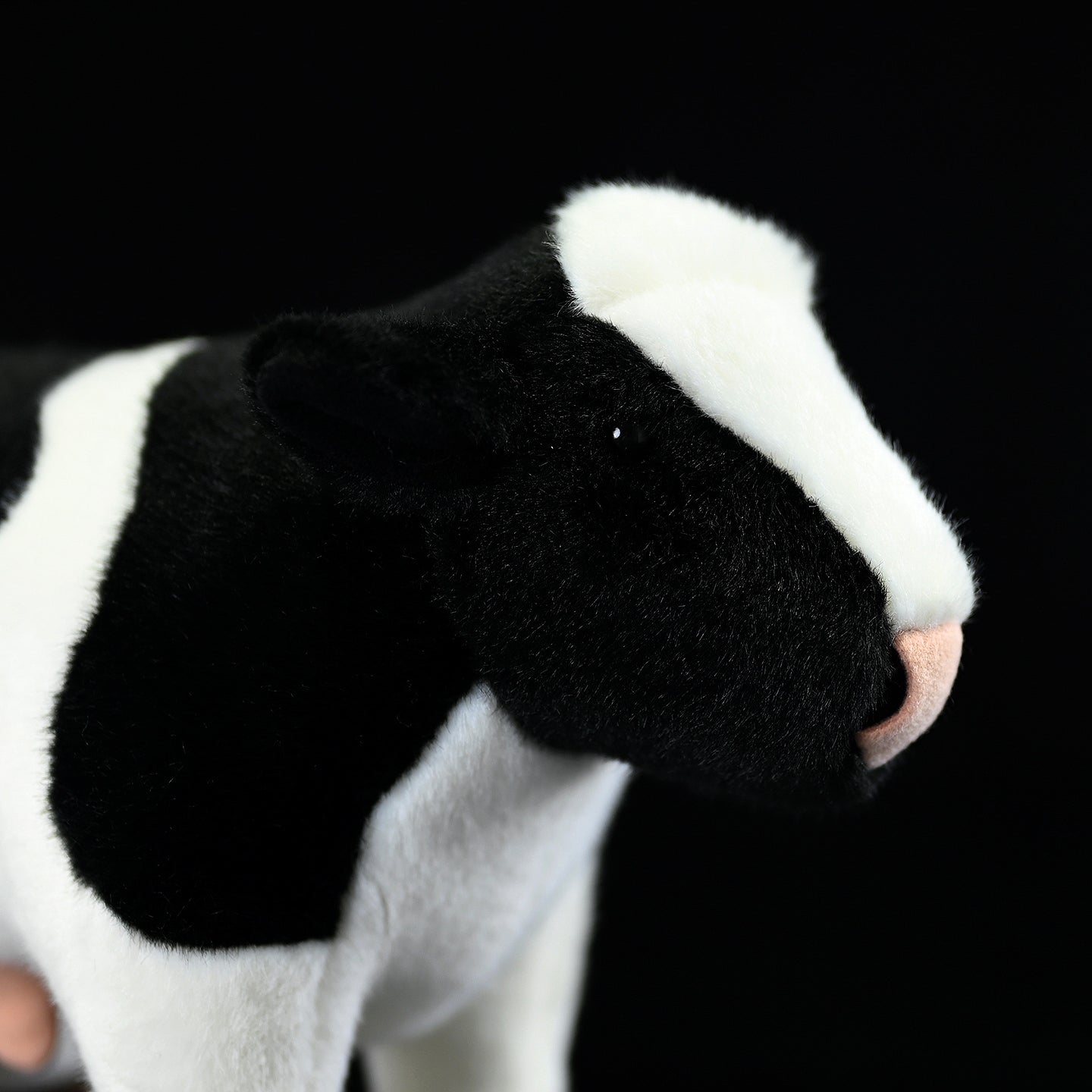 Detailed close-up of a plush Holstein cow’s head, with soft fabric and realistic black-and-white features