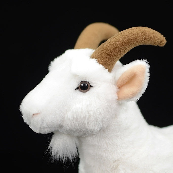 Close-up of the white goat plush toy's face, highlighting its realistic brown horns and soft fur