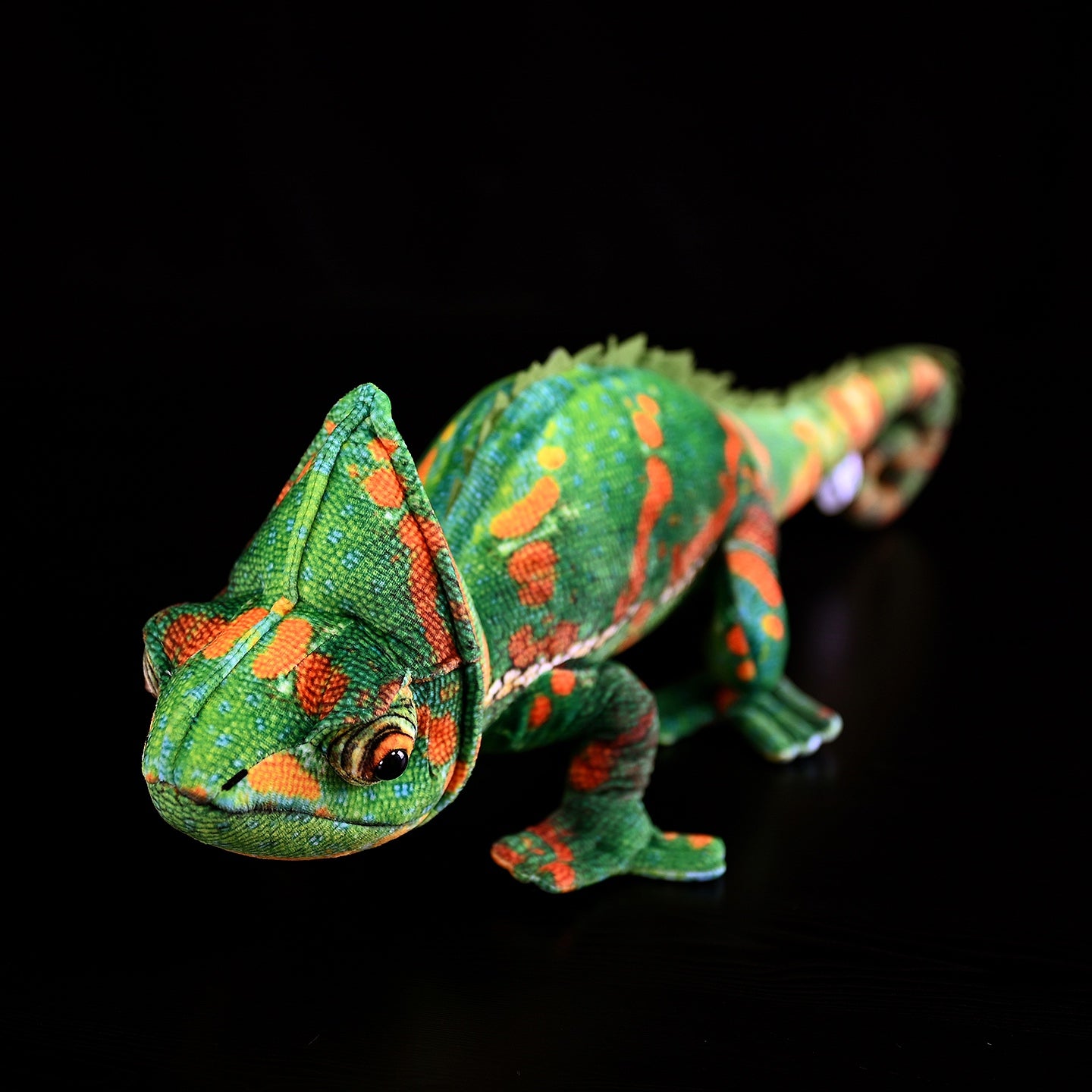 Close-up side angle of a veiled chameleon plush toy with lifelike features and vibrant textures