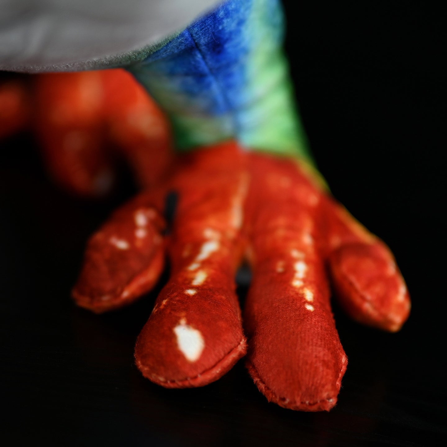 Close-up of SoftDaysLab red-eyed tree frog plush's bright orange feet, highlighting its realistic craftsmanship