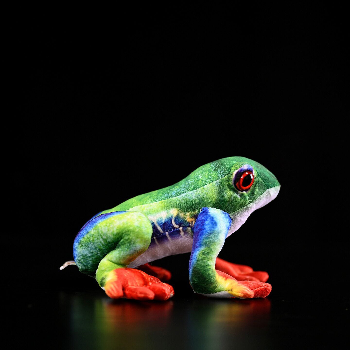 Profile of Red-Eyed Tree Frog Plush showing vivid blue legs and vibrant orange feet