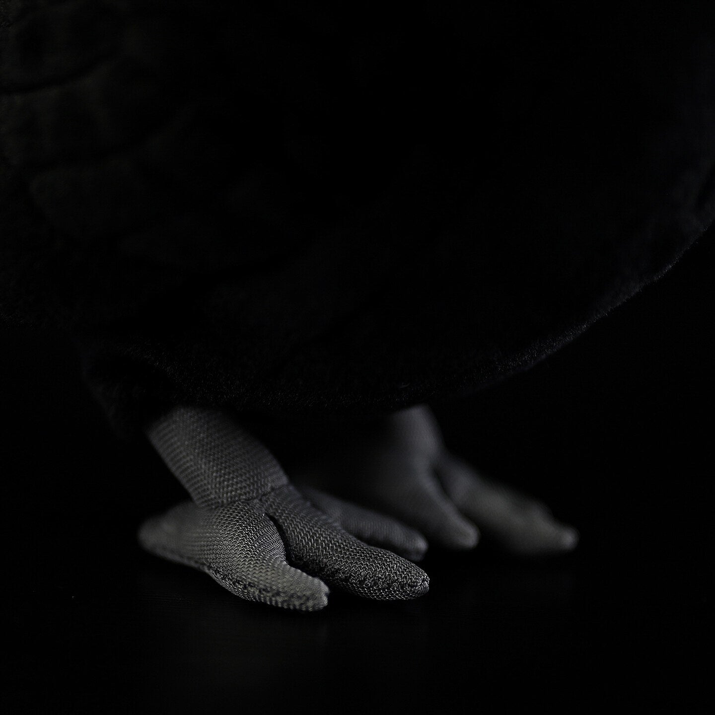 Close-up of the Eurasian Blackbird plush toy's gray feet with realistic stitching and soft texture