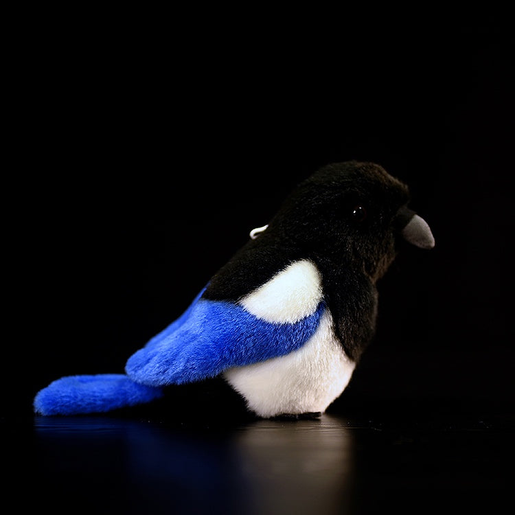Side view of a black-billed magpie plush toy with realistic iridescent blue-green wing accents and soft texture