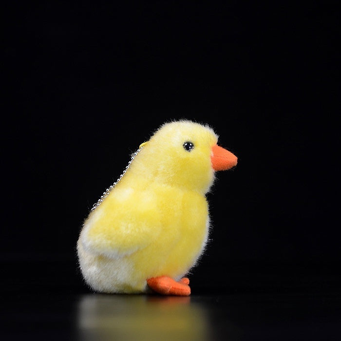 Side view of a lifelike yellow chick plush toy, showcasing its fluffy texture and adorable details