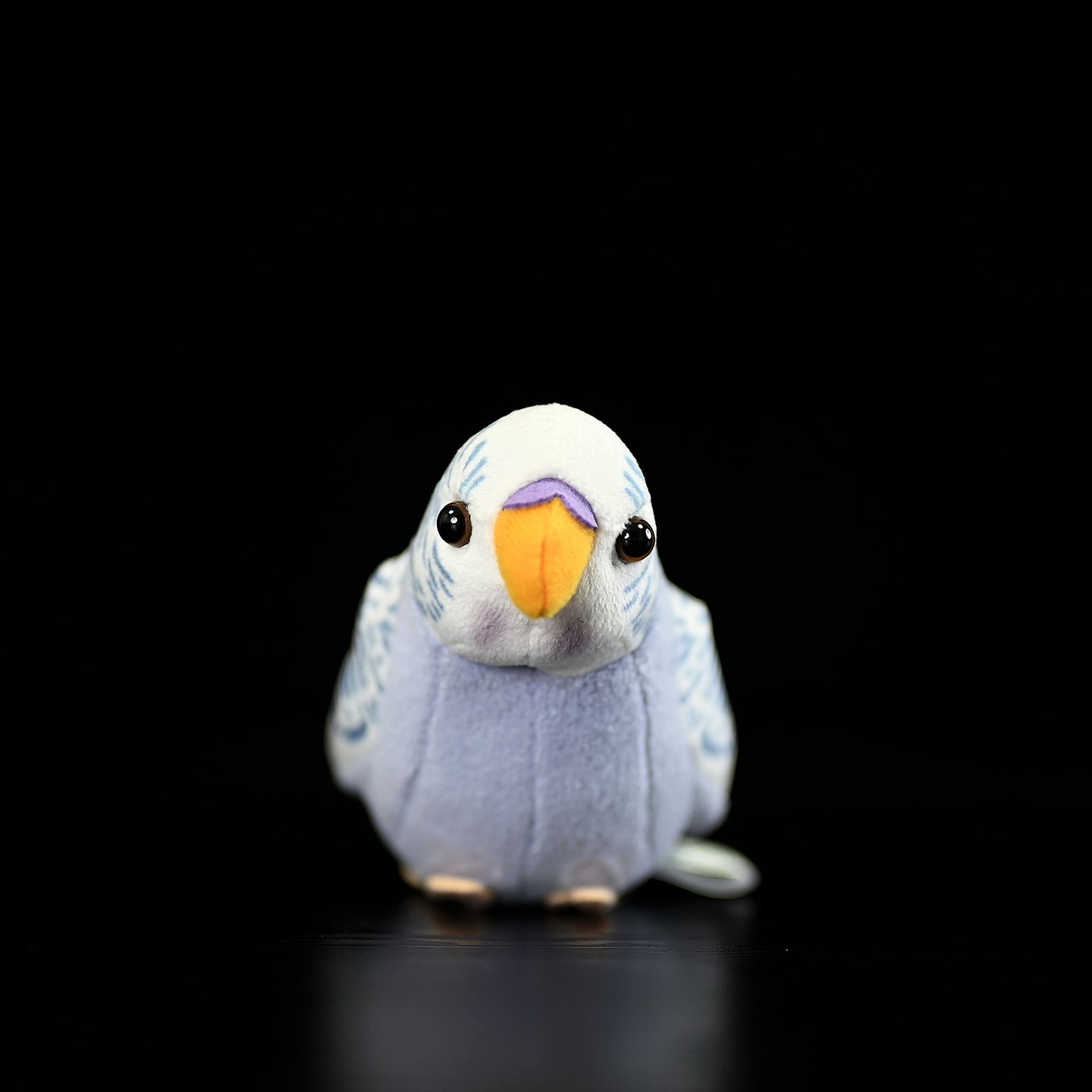 Front view of a violet budgerigar plush toy, showcasing its adorable face and vivid colors