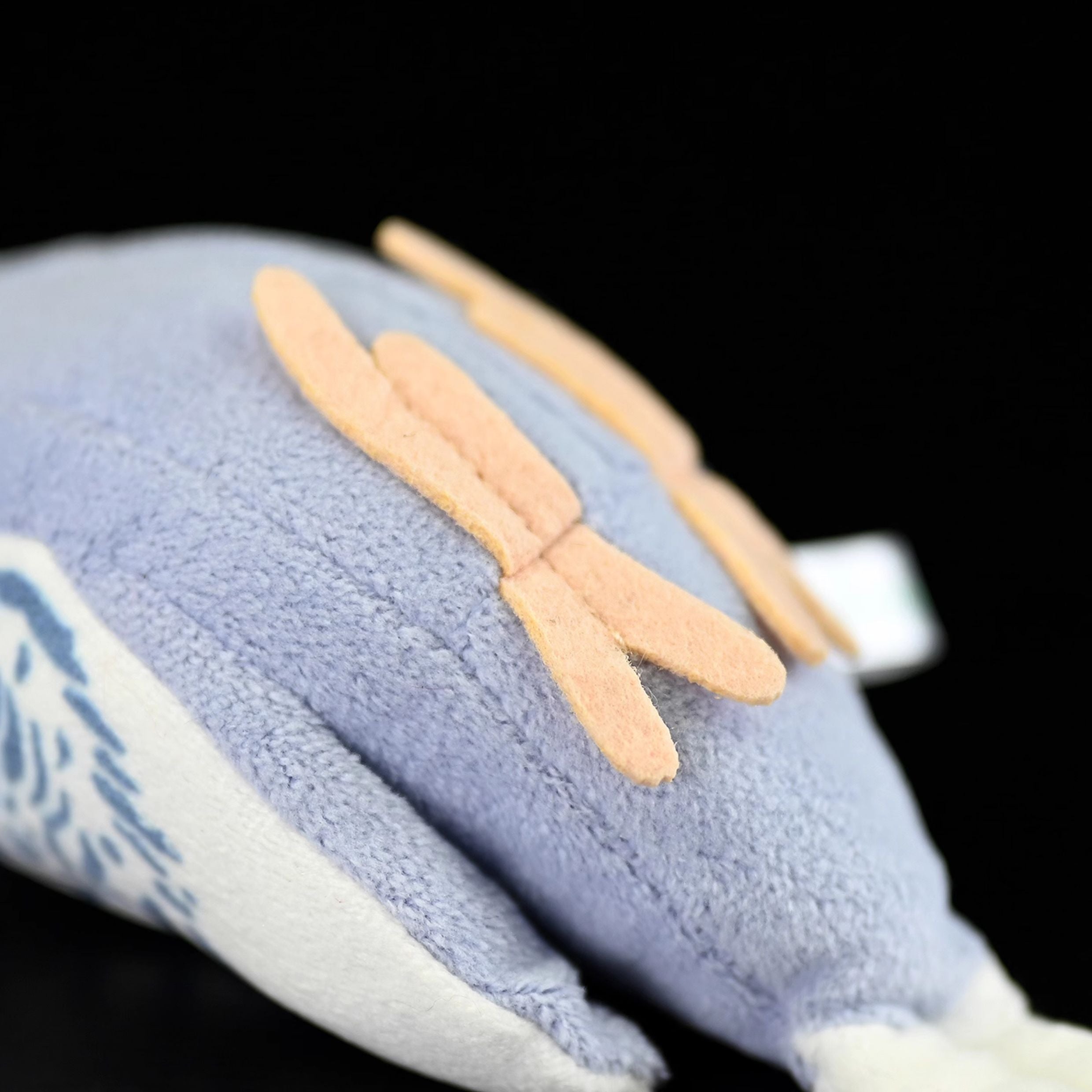 Bottom view of a violet budgerigar plush toy, showing its soft feet and quality craftsmanship