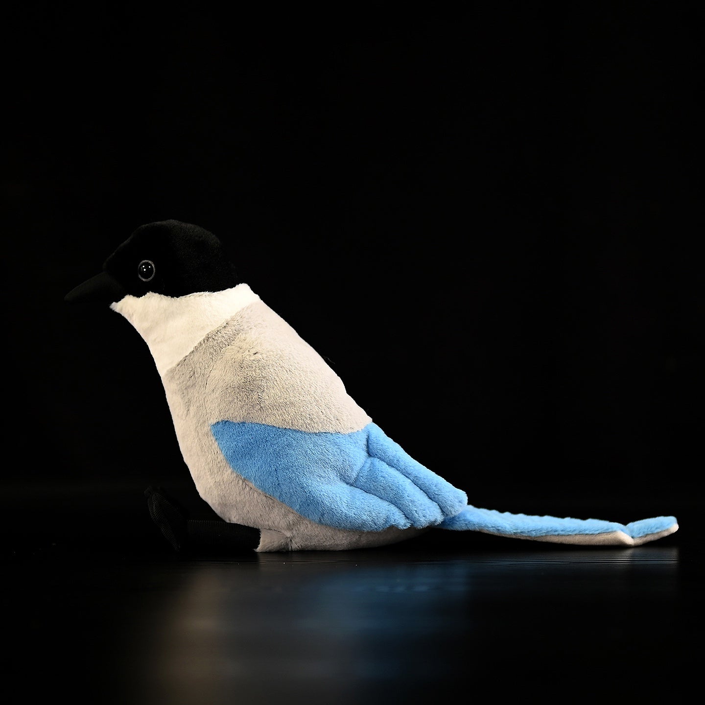 Side view of an azure-winged magpie stuffed toy with vibrant blue wings and a soft texture