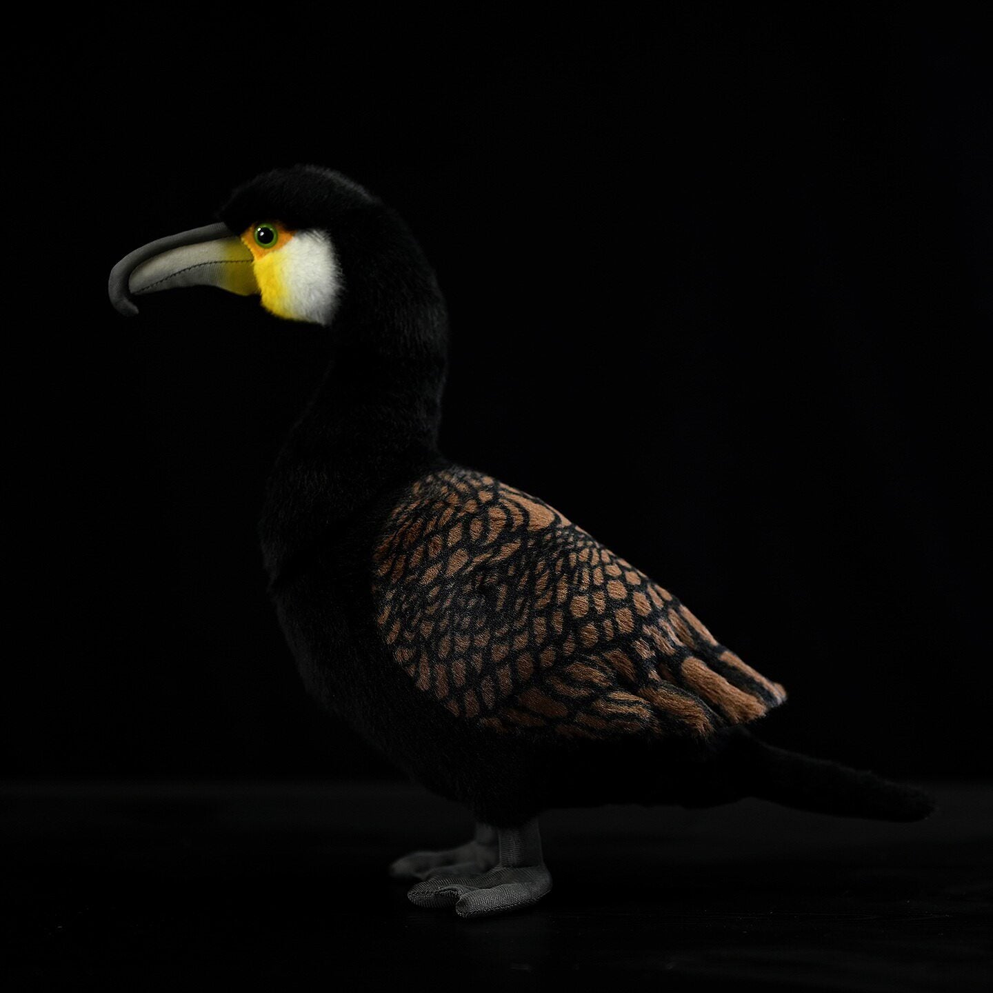 Side view of a realistic Great Cormorant plush toy with intricate wing details and vibrant yellow accents